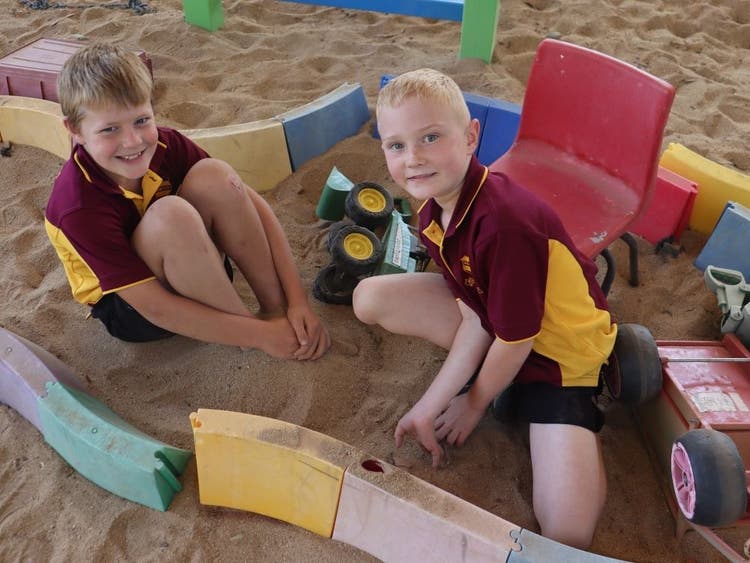 Students playing in the sandpit with trucks