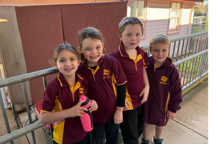 Students in Kindy to year 2 standing side by side smiling